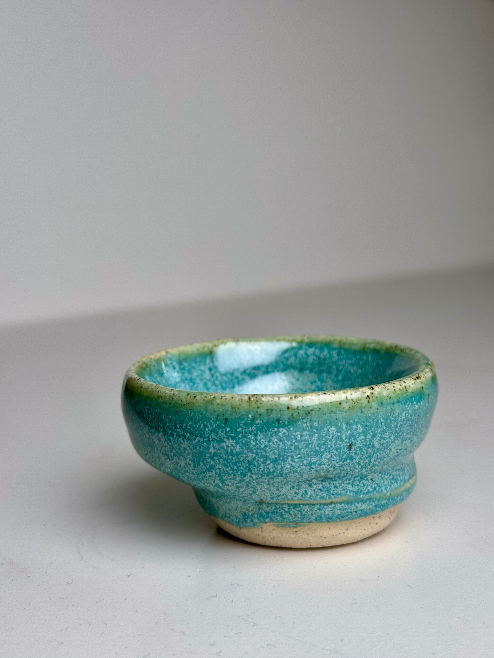 Green-Blue Gradient Cup Small handmade ceramic cup with flowing green-blue glaze over natural clay base, sitting on a white surface